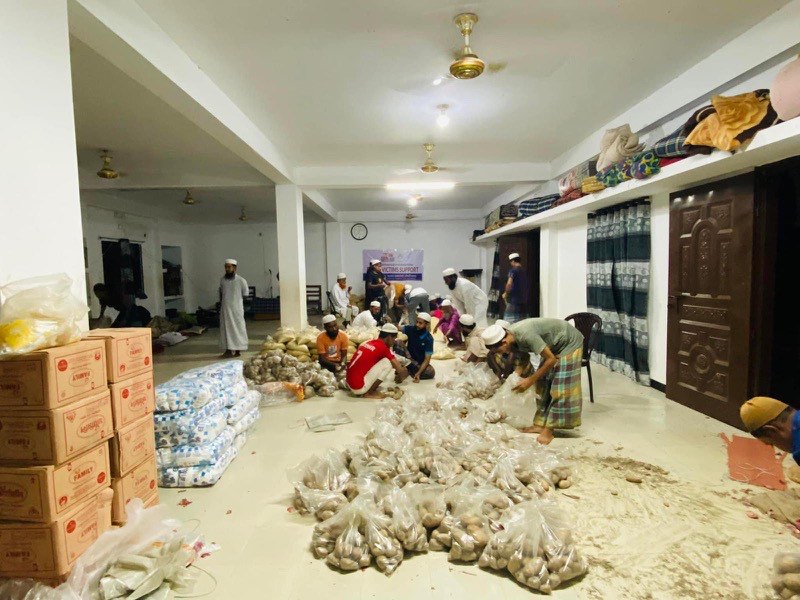 Volunteers packing fresh produce into food parcels on the floor at night